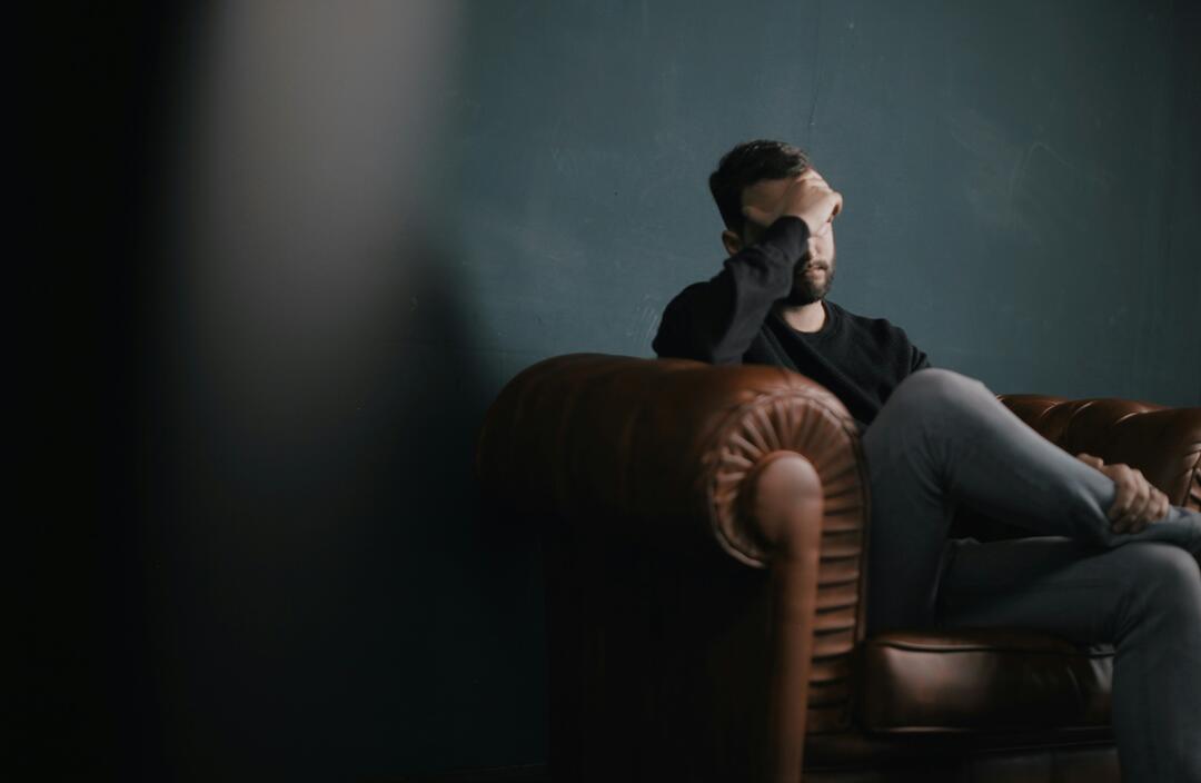 man sittling with hand on forehead